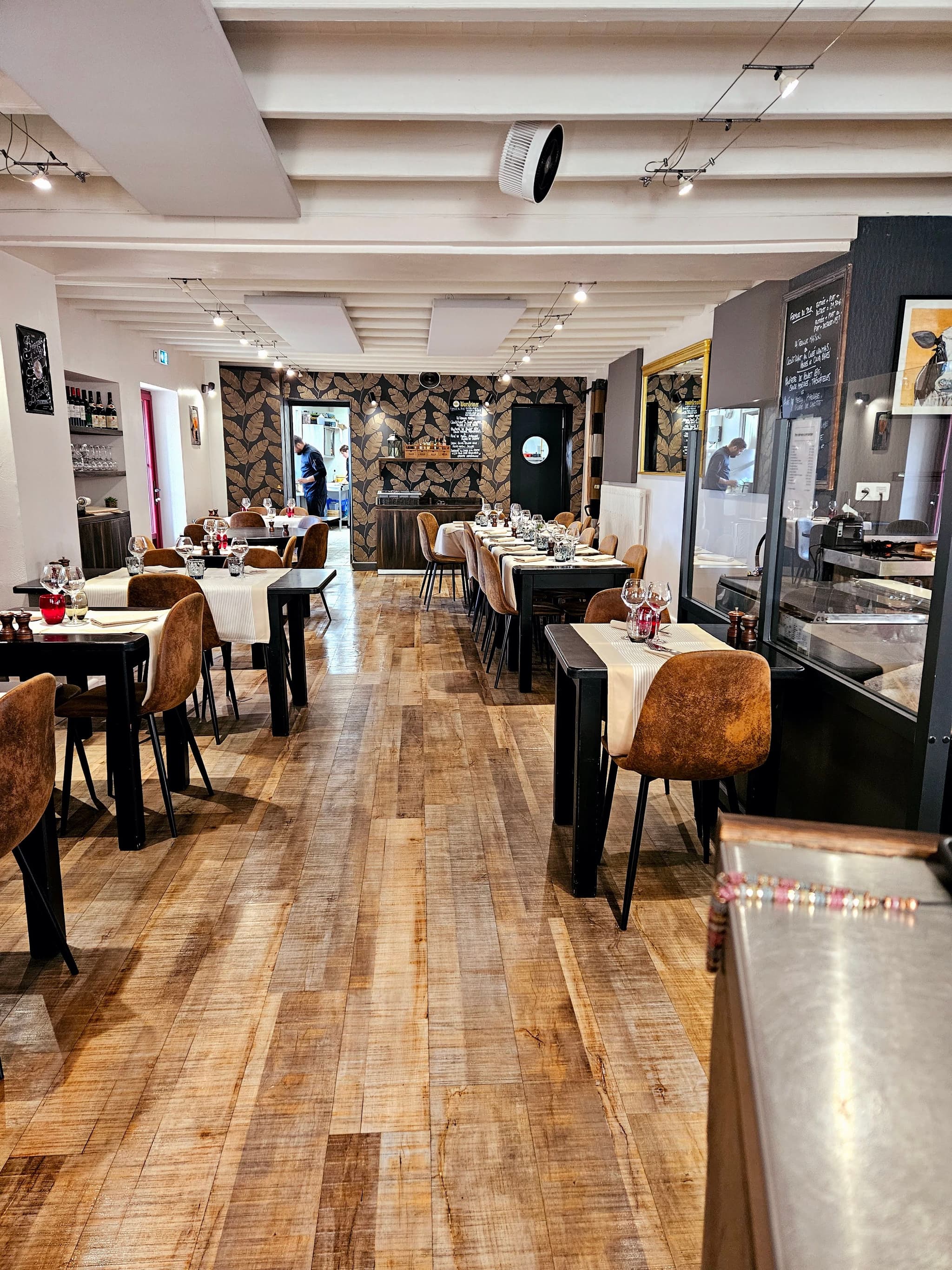 Salle du restaurant Table 23 à Carquefou, dressée avec élégance, vue sur la cuisine ouverte et décoration chaleureuse